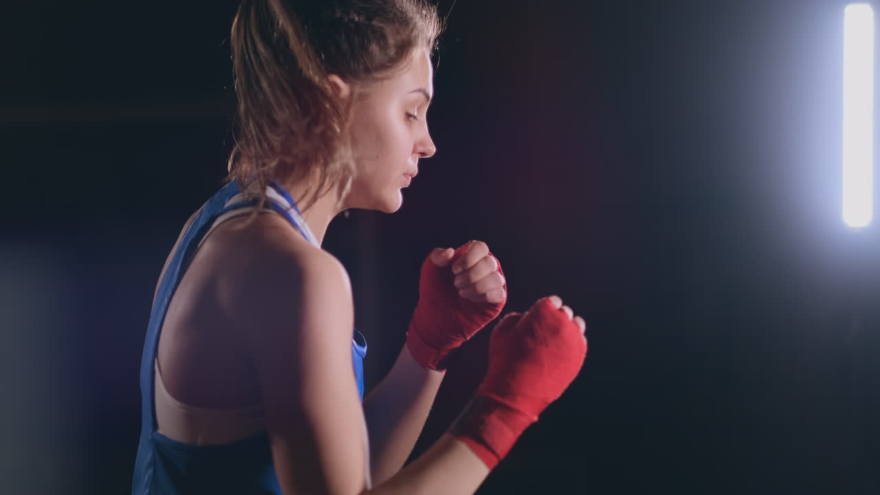 entrenamiento de boxeador femenino en una habitación oscura con luz de fondo en cámara lenta vista lateral. disparo de steadicam