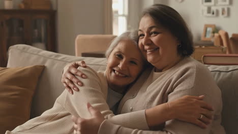 two happy senior women embracing on a sofa
