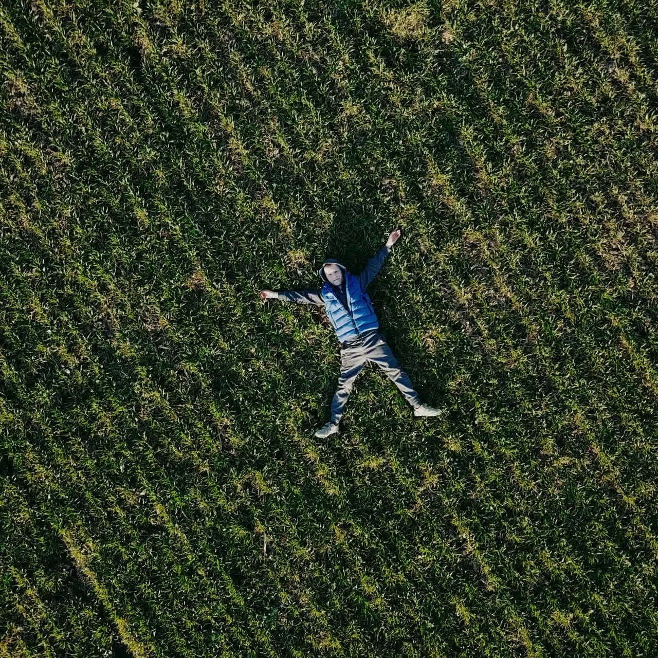 Little boy on a field in the sunlight enjoying nature. Aerial view Square video