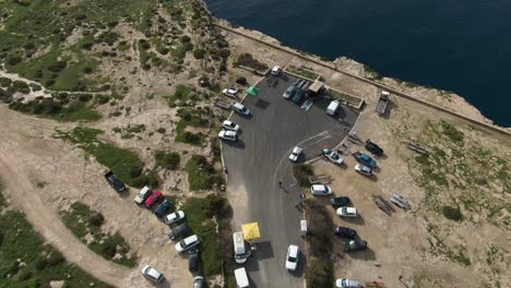 cars parked at the road end on top of the lush sandy hill by the sea coast - aerial shot