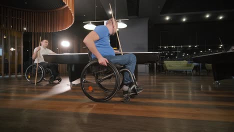 adult men with disabilities in a wheelchair play billiards in the club