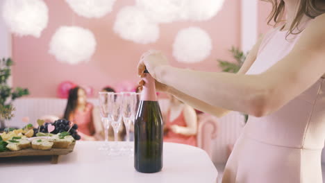 seitenansicht einer frau, die eine flasche champagner auf dem tisch öffnet