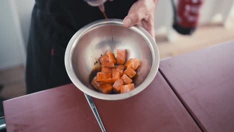 Ein-Professioneller-Koch-Fügt-Einer-Schüssel-Mit-Lachsstücken-Sojasauce-Hinzu-Und-Bereitet-So-Ein-Sushi-Gericht,-Traditionelle-Japanische-Küche,-Zu