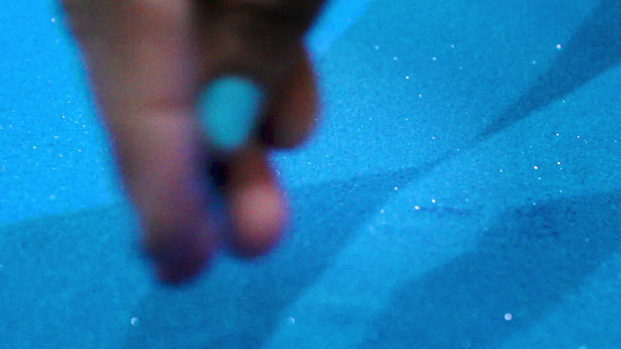 Hand gently spreads sparkling blue rangoli powder in close-up. Vibrant texture and subtle glitter capture traditional Indian art process for festive decorations like Diwali