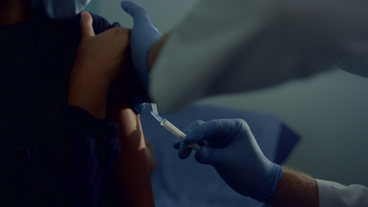 Closeup doctor hands injecting vaccine to african girl. Covid pandemic concept.