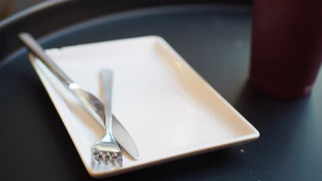 close-up of a chocolate chip cookie on a white plate with a fork and knife