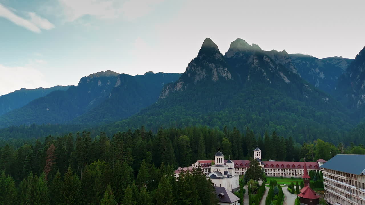 Calm mountain retreat view. A peaceful retreat nestles in the forest at the foot of towering mountains, surrounded by lush greenery and tranquility