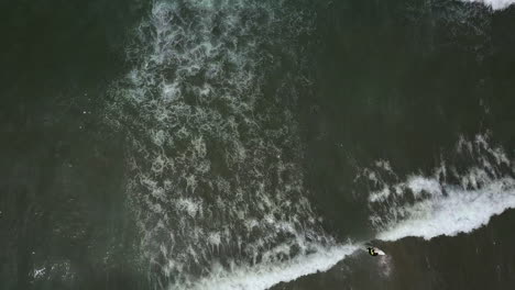 Vista-Superior-Aérea-De-Surfistas-Remando-Y-Montando-Olas-Pequeñas-En-La-Playa-De-California