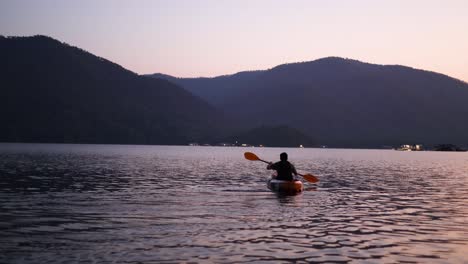 person kayaking on calm water as evening falls