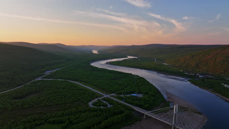 Aerial-tracking-shot-of-the-Sami-Bridge-and-the-Tenojoki-river,-dusk-in-Utsjoki,-Finland