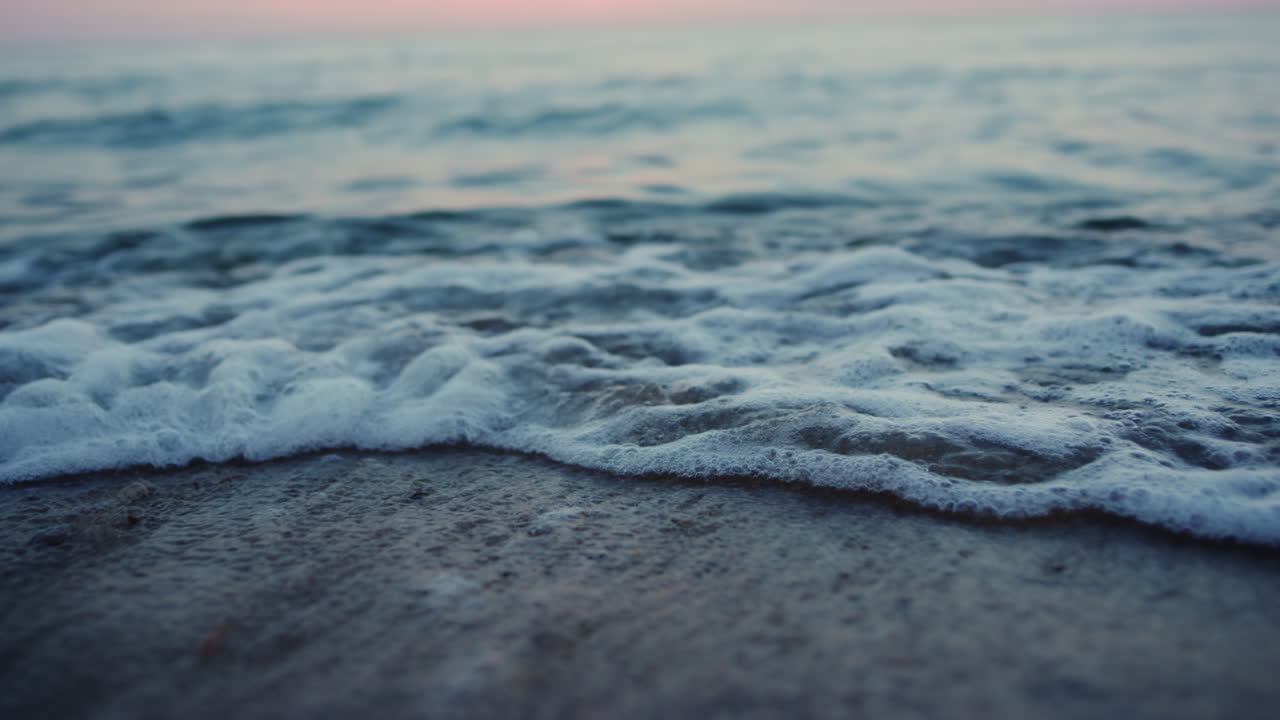 저녁 해변에 모래 해변을 깨는 바다 파도 해가 지고 새벽. 자연이 휴식을 취