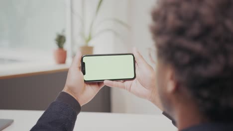 joven negro está viendo en la pantalla horizontal del teléfono y asintiendo con la cabeza, oficina establecida