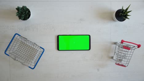 un teléfono con una pantalla chromakey verde y un carrito de compras en un fondo blanco. vista desde la parte superior del teléfono inteligente