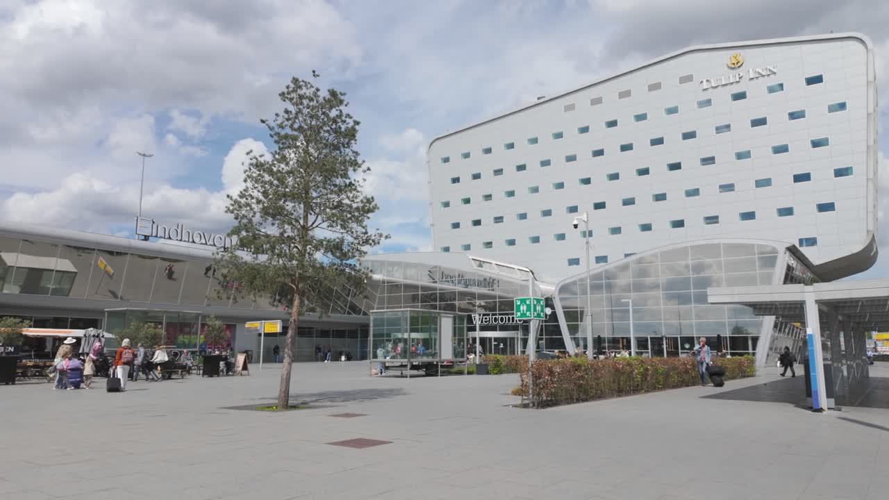 Pan shot of people walking towards Eindhoven Airport entrance, Netherlands