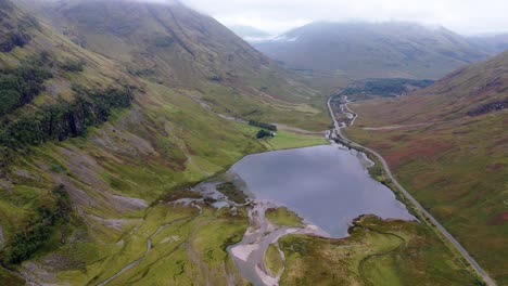 aerial drone footage of loch achtriochtan and the main road, a82 in the glencoe mountain range in the scottish highlands, taken in summer