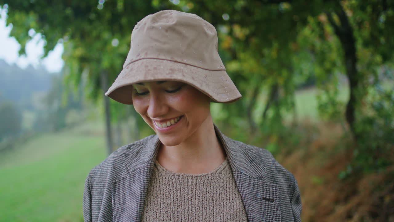 mujer sonriente con un sombrero de lluvia en un campo