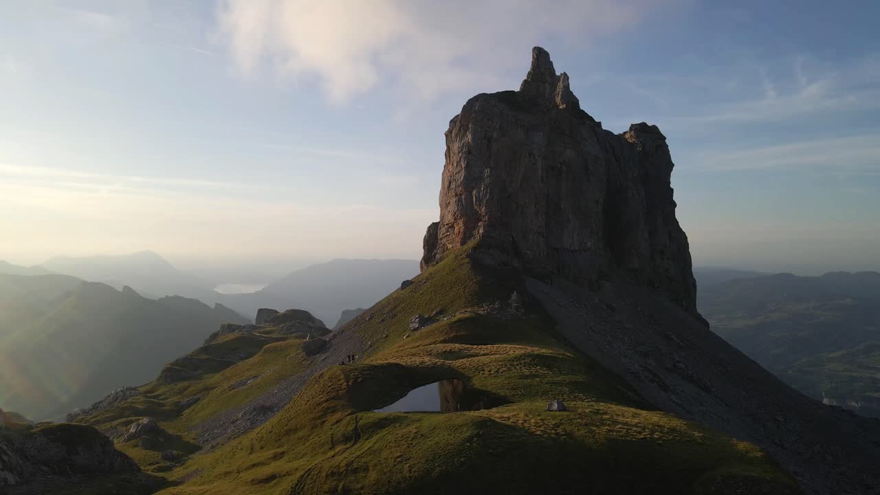 drone footage capturing breathtaking light over the Gross Achslenstock mountain peak showcasing the soft sunrise light illuminating the rugged terrain and tranquil surrounding of Schwyz, Switzerland