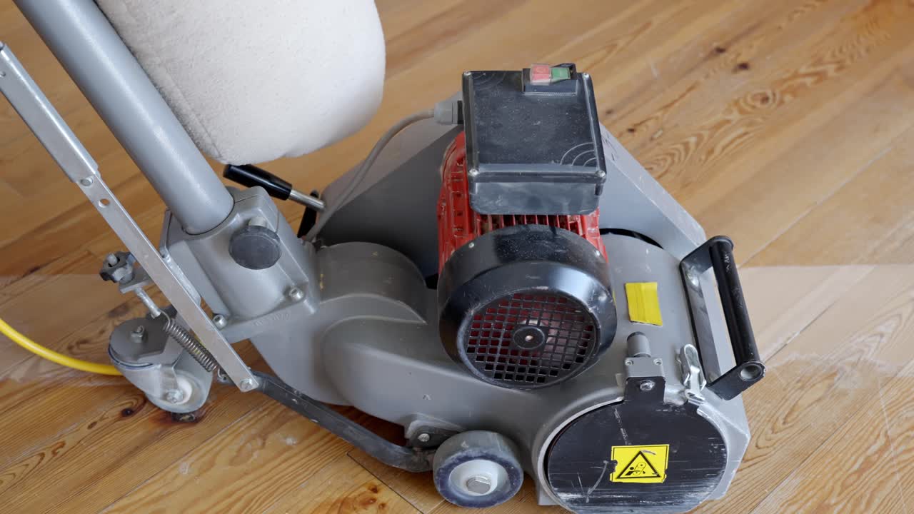 Operator starts sanding machine by pressing green button to refinish pine wood floors.