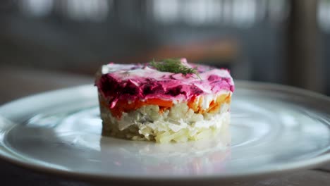 ensalada rusa tradicional con remolacha y verduras de arenque, en una mesa de madera en un plato blanco