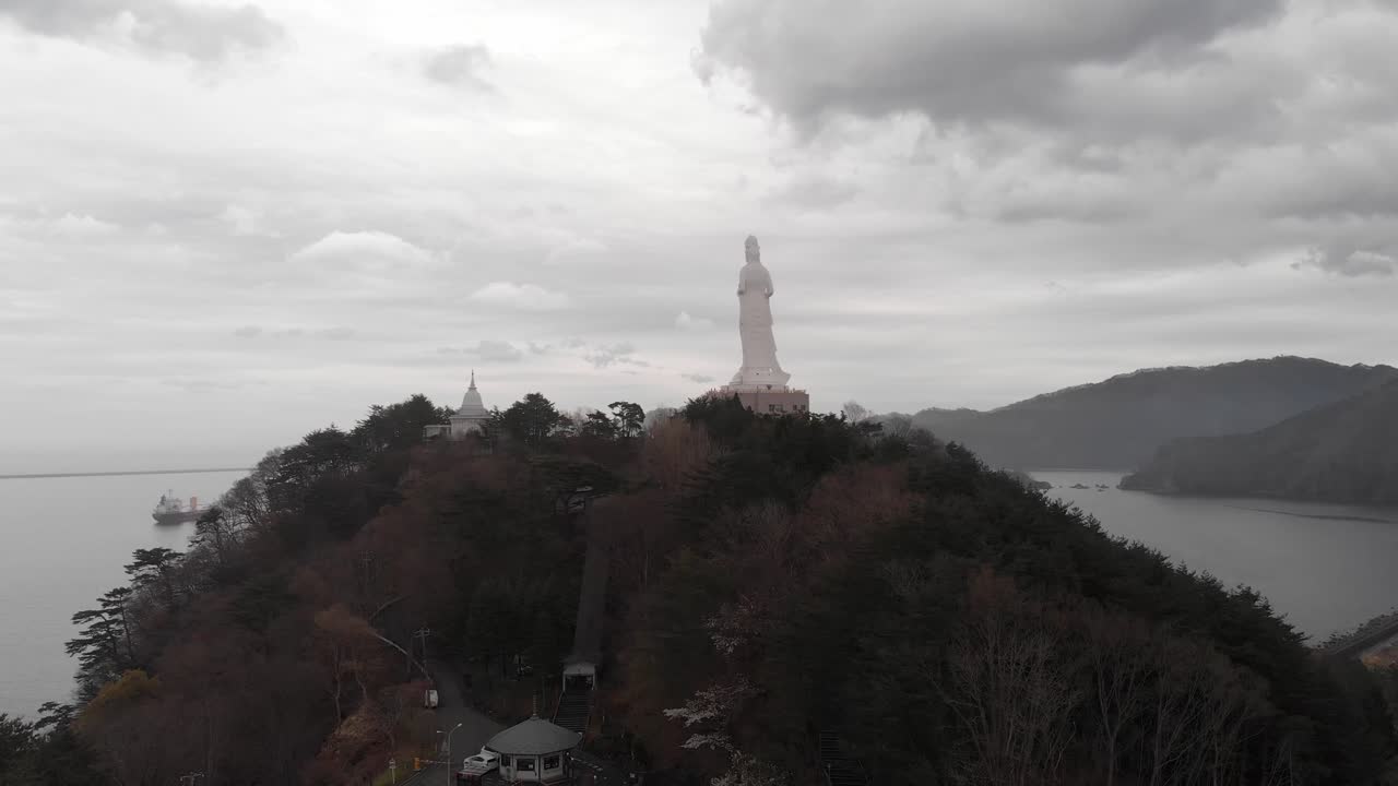 Aerial tilts up Aizu Jibo Dai Kannon Statue in Japanese Misty Mountain Sea Landscape