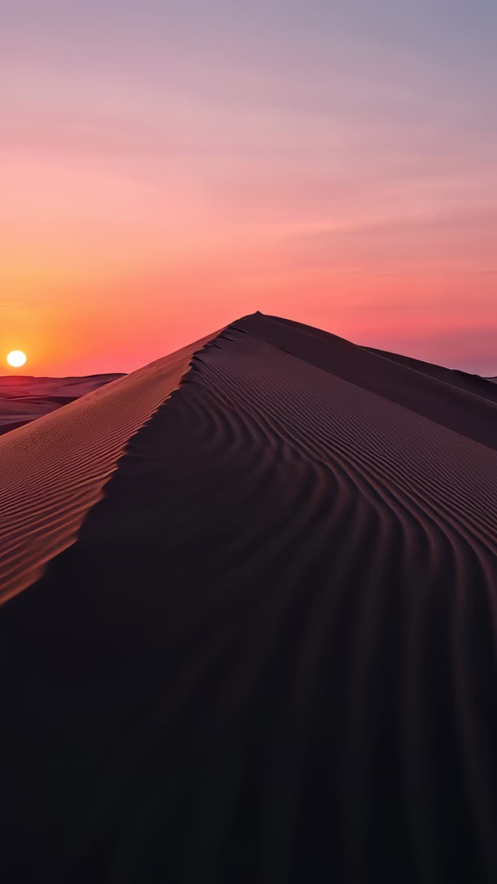 Vertical video: Moving camera along dune crest as sun sinking at left horizon, showing footprints