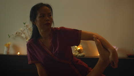 Asiatische-Frau-Führt-Bei-Schöner-Europäischer-Frau-Eine-Traditionelle-Thai-Massage-Durch.-Rehabilitation-Und-Behandlung-Nach-Verletzungen-Mit-Hilfe-Einer-Massage.-Entspannen-Und-Erholen-Sie-Sich-Von-Der-Massage-Der-Beine,-Arme-Und-Des-Rückens.-Therapeutische-Massage