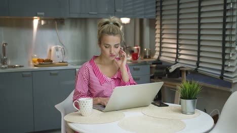 Young-woman-using-laptop-in-kitchen