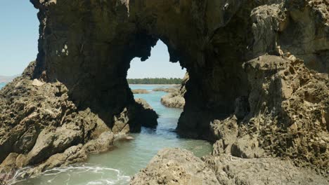 Cliffside-wonder:-Bird-gracefully-soars-through-a-captivating-hole-in-the-rugged-rock