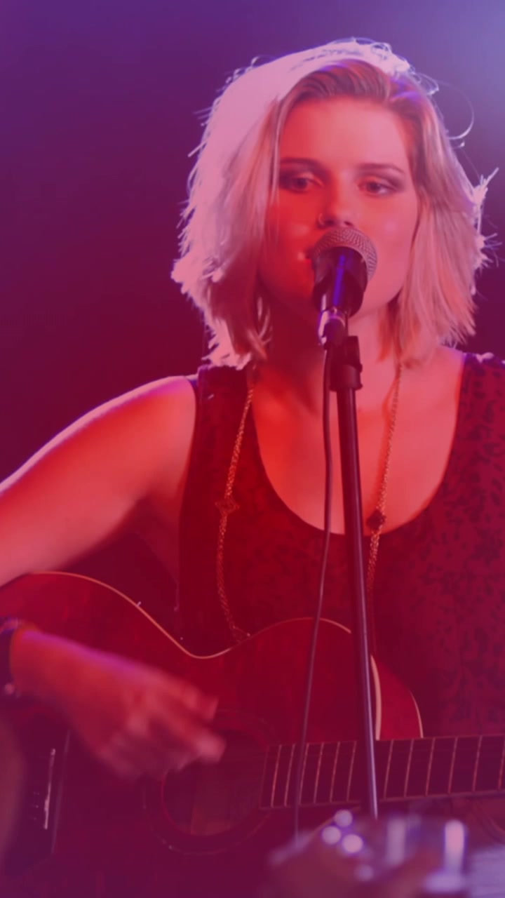 Animation of spots of light against caucasian female singer playing guitar and singing at a concert