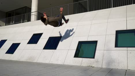 young parkour athlete doing a wall backflip of a modern building in 4k