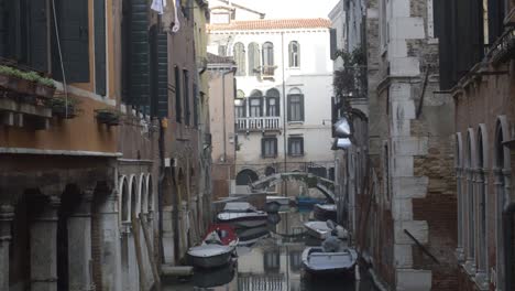 Personal boats parked between the walls of tall buildings built on the water.