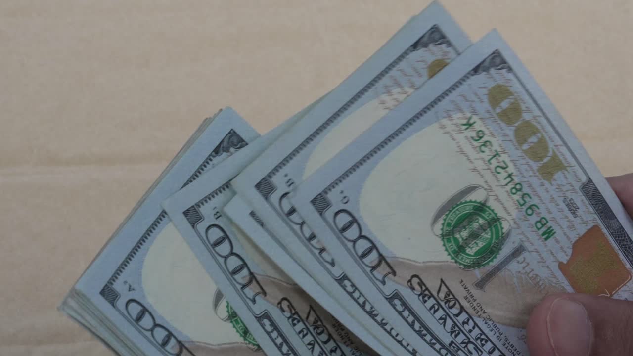Primo piano di mani che contano una pila di banconote da cento dollari USA. Denaro contante, valuta, concetto finanziario dettagliato. Video 4K.