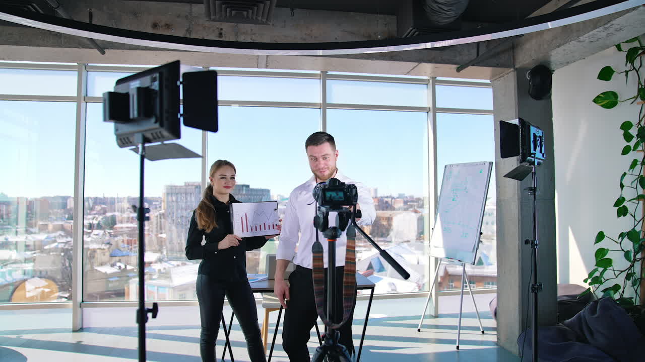 Young business people recording video. Handsome guy talking on camera inviting to join the project. Creative bloggers man and woman speaking on professional camera in studio.