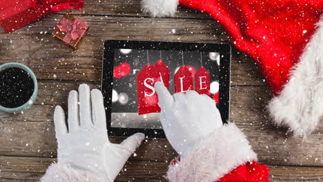 video composition with snow over desk  with santa hand on laptop