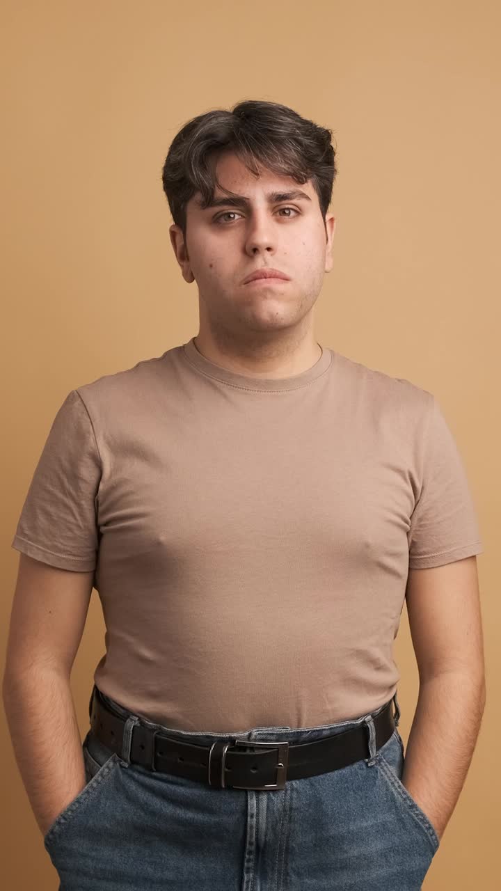 Serious young man looking at camera standing hands on pocket