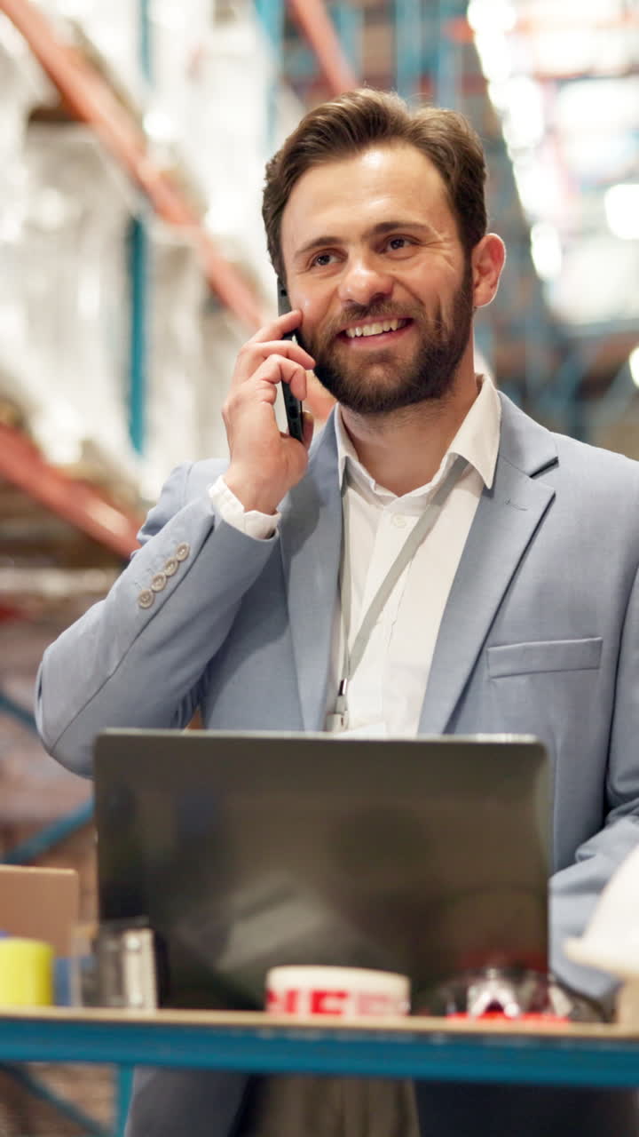 Mann im Lager, der am Telefon spricht, während er am Laptop arbeitet
