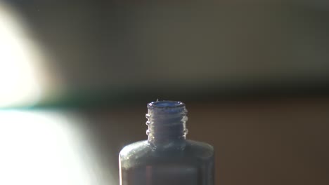 dipping nail brush in periwinkle polish. blue cosmetic product bottle