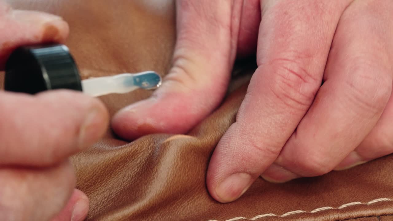Hands squeeze leather to expose cut, pour adhesive, then bond brown surface