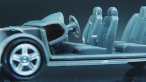 a tiny model metal sample skeleton of a car on a rotating stand with studio lights, macro close up shot, 4k video, silver wheels, black tires, doors and windows, plastic seats