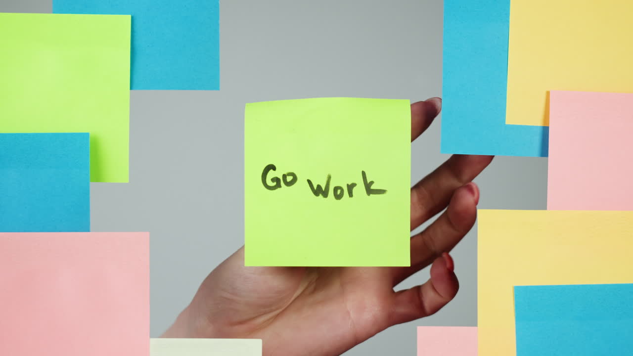 Hand Placing 'Go Work' Sticky Note on Wall