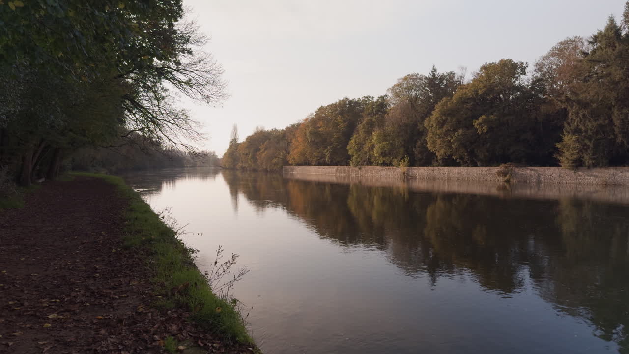 Calm autumn day along the Cher River with reflections of trees on the still water at golden hour