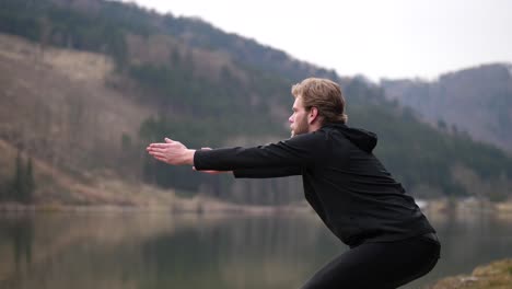 a man is doing squats next to a river in an autumn landscape