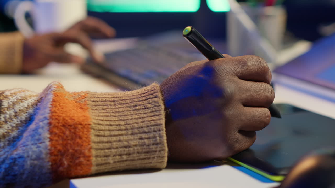 Close-up of a person using a digital pen and drawing tablet for creative work