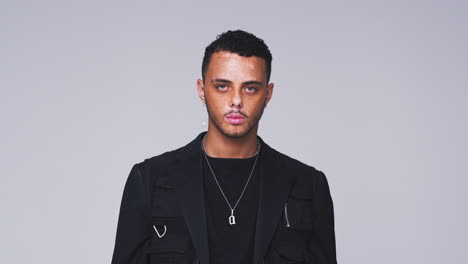 waist up studio shot of young man with skin pigmentation disorder smiling at camera in slow motion