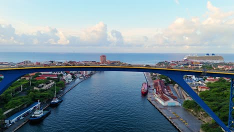 Drohne-Erklimmt-Die-Königin-Juliana-Brücke-In-Willemstad,-Curaçao,-Um-Gebäudefassaden-Und-Den-Karibischen-Ozean-Freizulegen