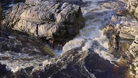 Nahaufnahme-Der-Starken-Flussströmung,-Wasser,-Das-Zwischen-Den-Felsen-Fließt-Und-Spritzer-Erzeugt