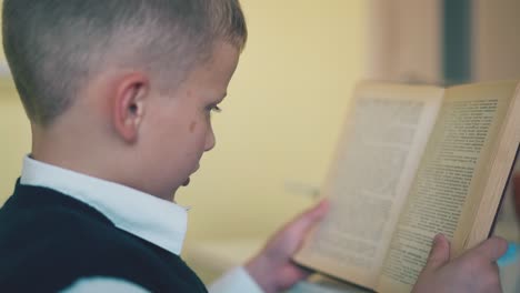 kid in school uniform does home task at table in room