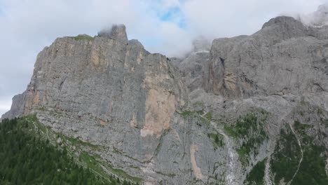 cinematic aerial footage of a drone ascending towards the selva rugged mountain range near passo gardena, dolomites