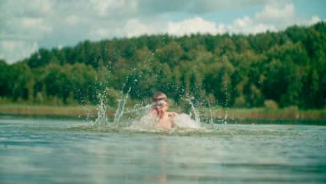 A-joyful-Caucasian-kid-splashes-the-water-in-the-lake,-Abstract-view-of-nature-in-the-background