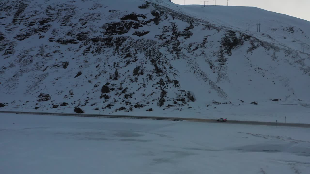 Supercar driving through a cold winter landscape in Northern Norway. Aerial follow shot